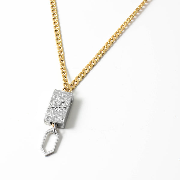 The Anne Marie Chagnon Borocay Necklace features a medium weight gold cuban link style chain with a rectangular pewter pendant with a suspended hexagon bead detail