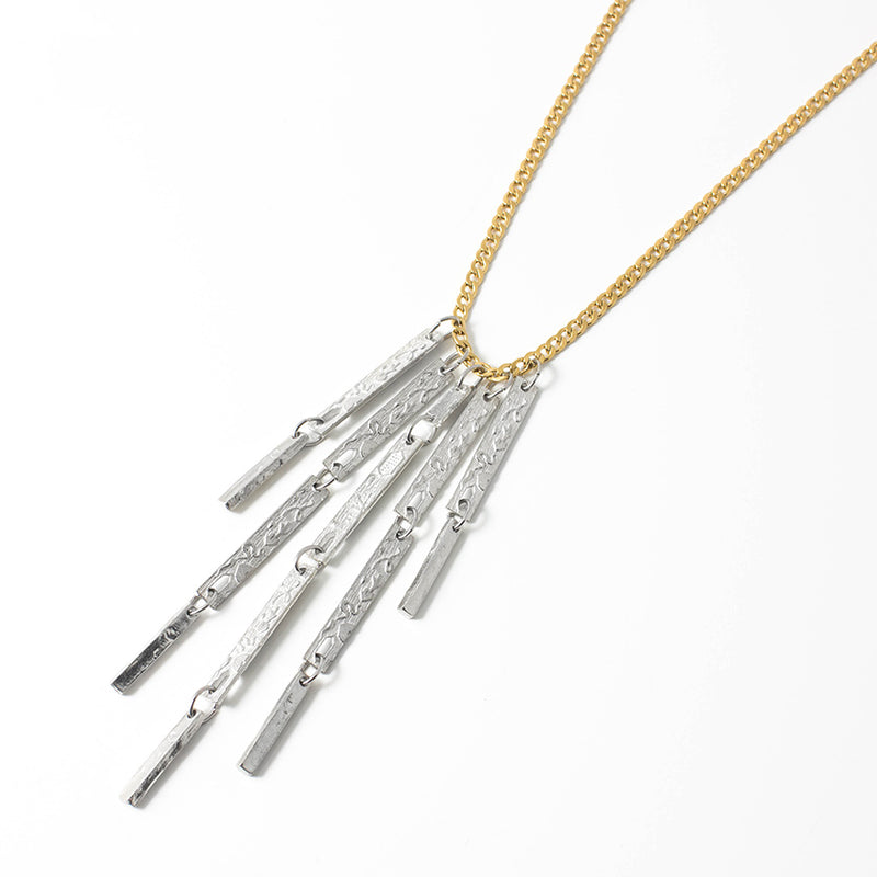 The NASSAU NECKLACE ANNE MARIE CHAGNON features a small weight gold cuban link style chain with a pewter pendant of textured bar beads of varying lengths