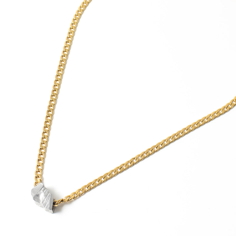 The Anne Maria Chagnon Athenes Necklace features a medium weight gold cuban link style chain with an organically textured drop of pewter as the pendant